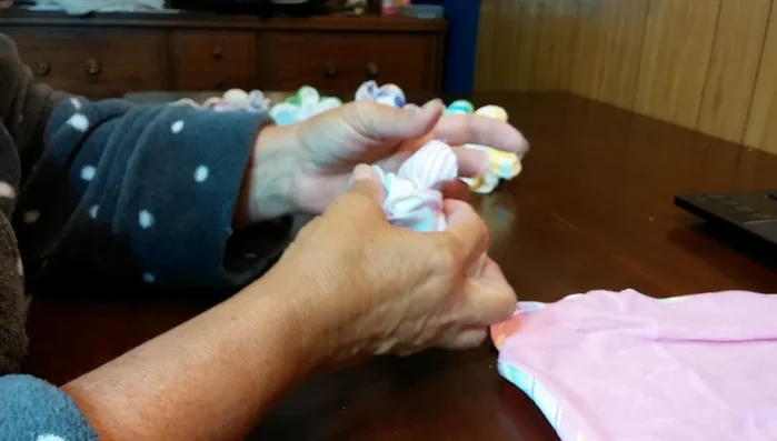 Work with the fabric, pulling and shaping the petals to create a rose-like shape.