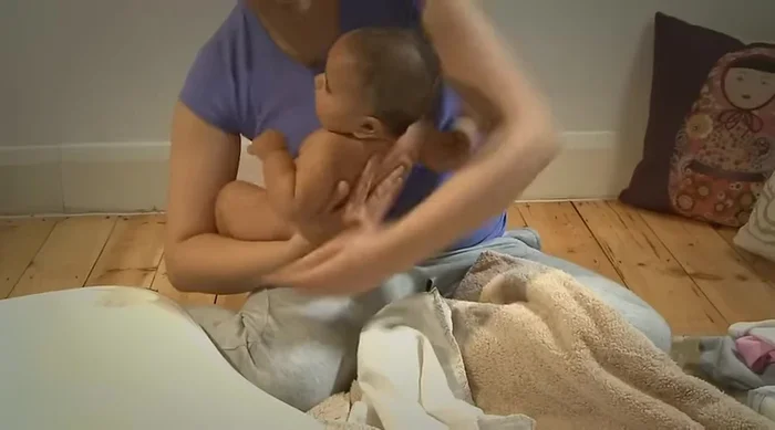 Secure your baby: Support your baby's shoulders and neck with one hand, and their bottom with the other. Gently lower them into the bath water, talking to them reassuringly.