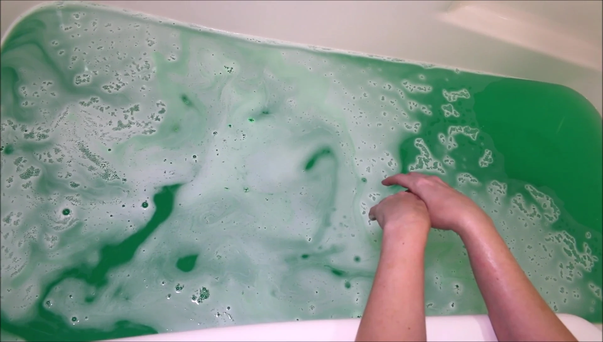 The bath water after the bath bomb has fully dissolved, showing the vibrant green color.