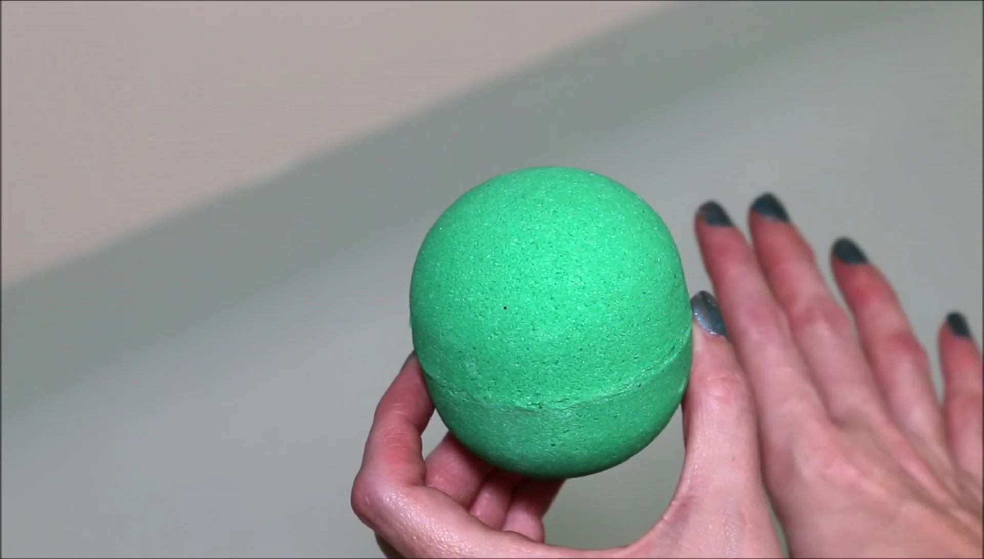 The bath bomb being held, emphasizing its size and shape.