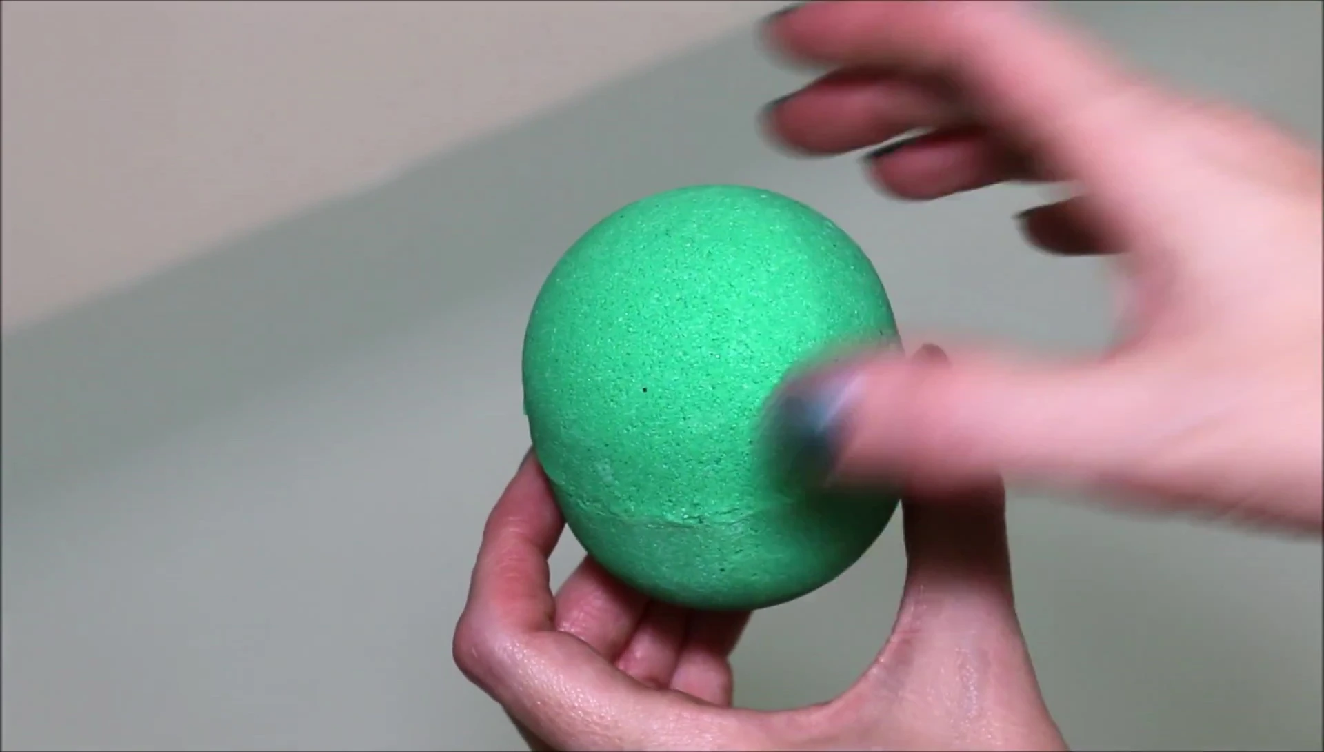 The bath bomb being placed in the water, initiating the fizzing process.