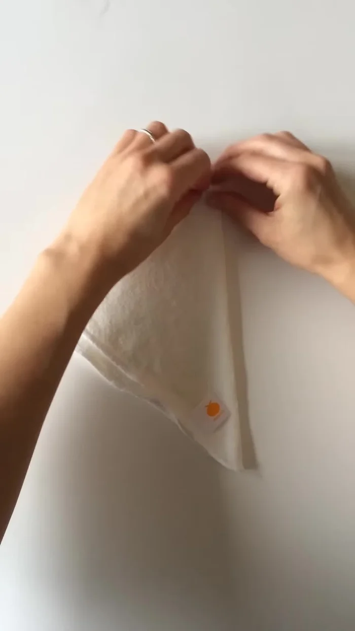 Continue folding in the same direction, folding the top down by about a quarter inch.