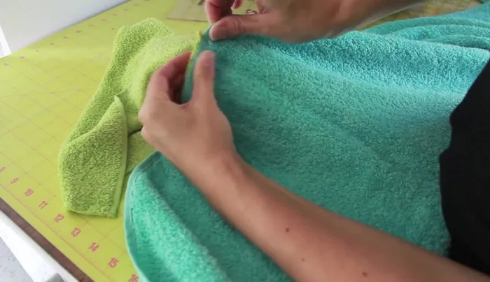 Zigzag stitch the seam between the hood and the bath towel to prevent fraying, using a dense zigzag stitch and backstitching.