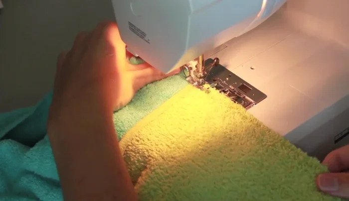 Zigzag stitch the seam between the hood and the bath towel to prevent fraying, using a dense zigzag stitch and backstitching.